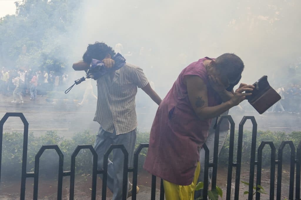 Protesters cover their faces after police fired tear gas shells near Parliament House, at the Windsor Place roundabout, Le Méridien hotel, in New Delhi, Monday, July 20, 2026. Photo: PTI/Atul Yadav.