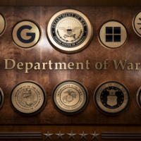 Logos of major tech companies with defense contracts (left to right: Meta, xAI, Google, Microsoft, Anthropic, OpenAI) added to a photo of Pentagon plaques showcasing the US armed services. Photo illustration by Thomas Gaulkin; source photo by Celal Güneş / Anadolu