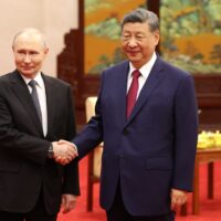 Vladimir Putin and Xi Jinping shake hands.