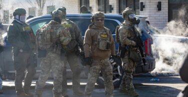 Several federal agents gather as people protest near the scene of 26th Street West and Nicollet Avenue in Minneapolis, where federal agents shot and killed Alex Pretti Saturday, Jan. 24, 2026. (Photo by Nicole Neri/Minnesota Reformer)