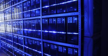 Server racks in a data center, bathed in blue light.