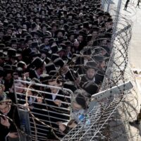 An Israeli soldier stands guard as young men gathered during a demonstration by Ultra-Orthodox Jews against Israel's military draft on June 17, 2026 outside the Beit Lid military base in Kfar Yona, Israel. Photo by Amir Levy/Getty Images.