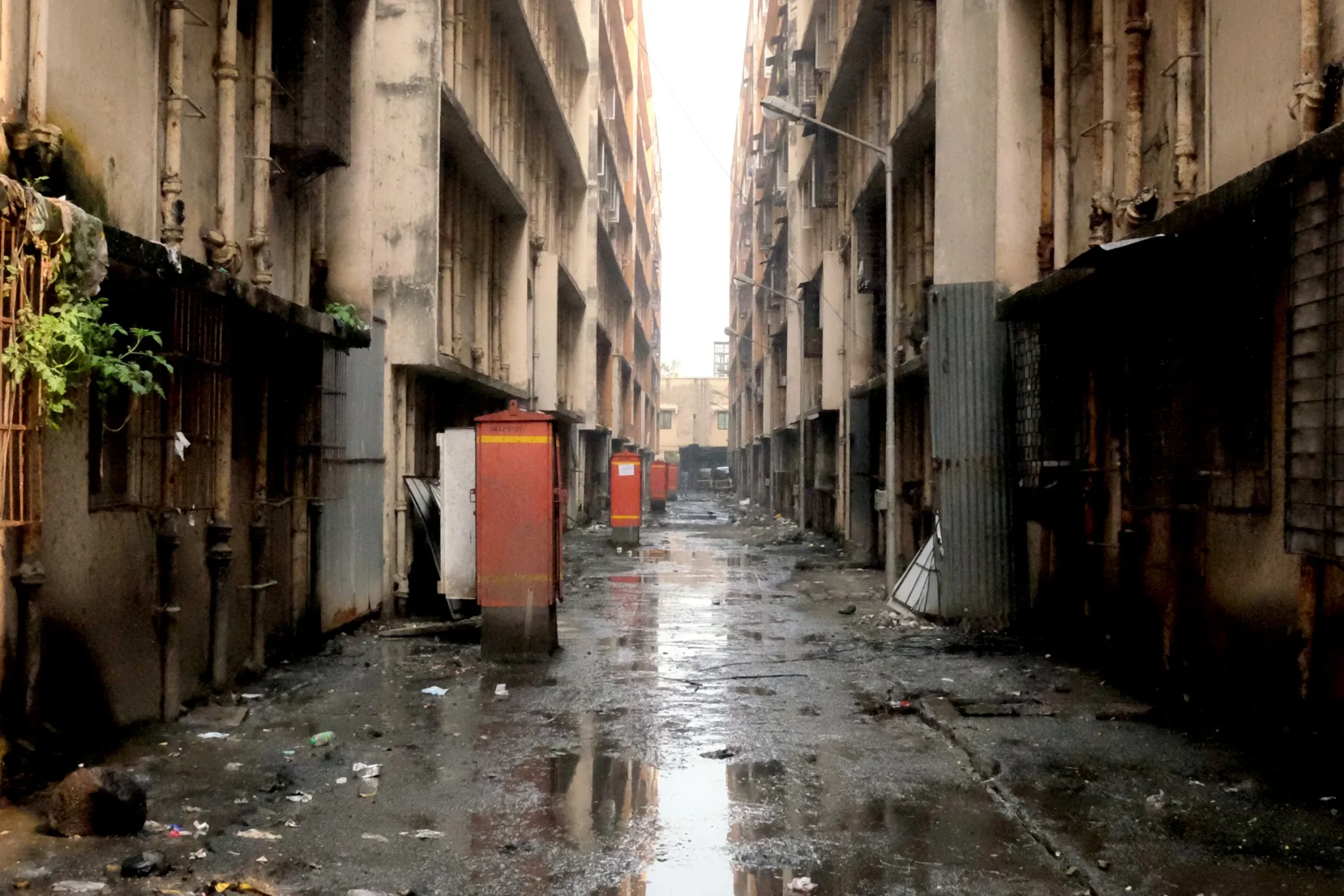 A damp alleyway between two tall, dilapidated apartment buildings.